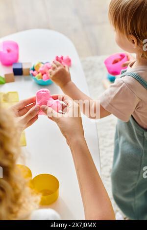 Eine lockige Mutter und ihre Kleinkind-Tochter lernen Montessori mit bunten Teig. Stockfoto