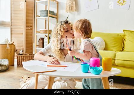 Eine Mutter mit lockigen Haaren und ihre Tochter sitzen an einem Tisch, um Montessori-Aktivitäten zu fördern. Stockfoto