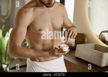 Ein Mann in einem Handtuch, der Creme aufträgt. Stockfoto