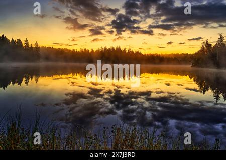 Der kleine Moorsee Etang de la Gruère im Schweizer Kanton Jura. Die Stimmung am Morgen kurz vor und nach Sonnenaufgang Stockfoto