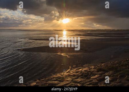 Während die Sonne untergeht, schweben Cumulus-Wolken am Himmel über dem ruhigen Gewässer und schaffen eine atemberaubende natürliche Landschaft am Horizont während der Dämmerung Stockfoto