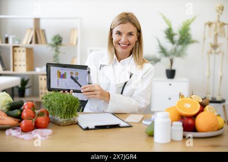 Glückliche Ernährungsberaterin präsentiert neue App zur Kalorienberechnung. Stockfoto