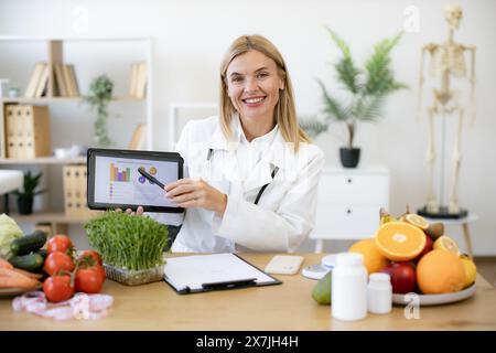 Glückliche Ernährungsberaterin präsentiert neue App zur Kalorienberechnung. Stockfoto