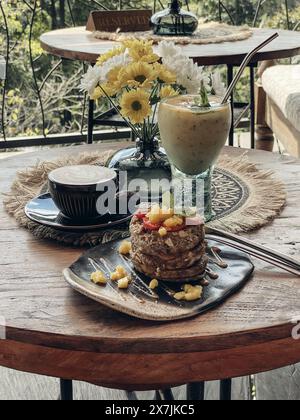 Eine Tasse Kaffee mit Latte Art auf Holztisch mit Pfannkuchen Stockfoto