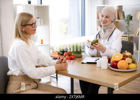 Ernährungswissenschaftler spricht mit Patienten über die Vorteile einer gesunden Ernährung Avocado halten. Stockfoto