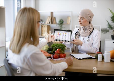 Professionelle Ernährungswissenschaftlerin erzählt den Patienten über die Vorteile einer gesunden Ernährung. Stockfoto