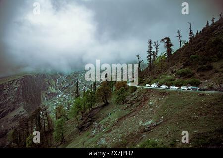 Ein majestätisches Panorama des schneebedeckten Himalaya in Himachal Pradesh, mit üppigen grünen Tälern und nebeligen Gipfeln, die den Himmel küssen. Friedliche Dörfer säumen das ganze Stockfoto