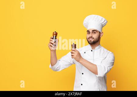 Professioneller Koch mit Shaker auf gelbem Hintergrund. Leerzeichen für Text Stockfoto