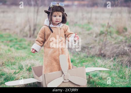 Charmantes Baby in Fliegerkleidung im Pappflugzeug. Stockfoto