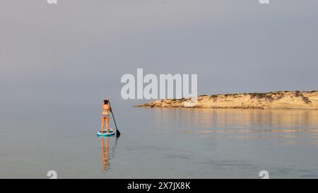 Mai 2024: Junge Frau paddelt in einem ruhigen Meer in der Coral Bay bei Pafos, Zypern. Stockfoto