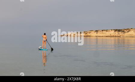 Mai 2024: Junge Frau paddelt in einem ruhigen Meer in der Coral Bay bei Pafos, Zypern. Stockfoto