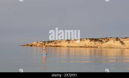 Mai 2024: Junge Frau paddelt in einem ruhigen Meer in der Coral Bay bei Pafos, Zypern. Stockfoto