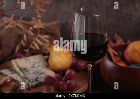 Herbstpicknick mit Wein- und Käseplatte, Früchten und trockenen Blättern Stockfoto