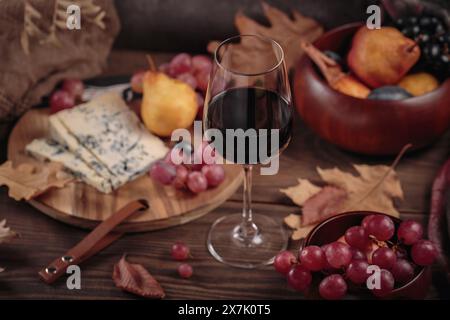 Herbstpicknick mit Wein- und Käseplatte, Früchten und trockenen Blättern Stockfoto