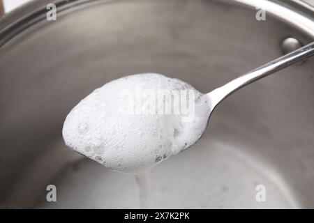 Chemische Reaktion von Essig und Backpulver in Löffel über Topf, Nahaufnahme Stockfoto