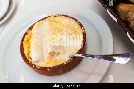 Appetitliche spanische Art gebackene Cannelloni gefüllt mit Fleisch in Sahnesauce serviert in Töpferwaren Stockfoto