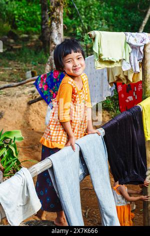 Glückliche Lahu-Kinder, die in einem Dorf in der Nähe der Lanjia Lodge in Chiang Khong in der Provinz Chiang Rai im Norden Thailands zum Trocknen aufhängen Stockfoto