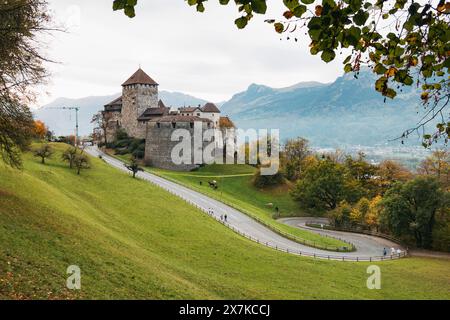 Eine gewundene Straße führt hinauf zum Schloss Vaduz auf einem Hügel, umgeben von Herbstbäumen. Die offizielle Residenz des Fürsten von Liechtenstein Stockfoto