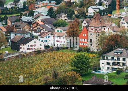 Traditionelle europäische Häuser und Weinberge in Liechtenstein, mit üppigem Grün und lebhaften Herbstfarben, einschließlich des Roten Hauses (EST. 1336) Stockfoto