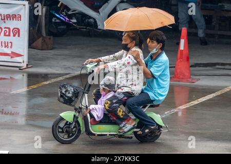 SAMUT PRAKAN, THAILAND, 20. März 2024, Eine Familie mit Regenschirmen fährt mit einem Elektrofahrrad im Regen Stockfoto