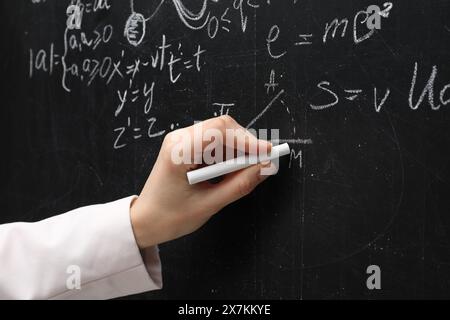 Lehrer schreibt physikalische Formeln mit Kreide auf schwarzer Tafel, Nahaufnahme Stockfoto