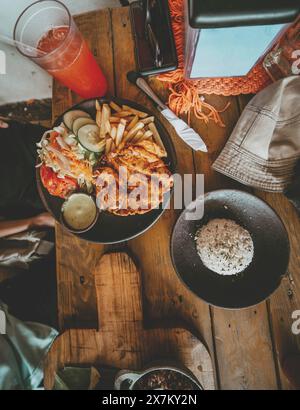 Blick von oben auf traditionelles gebratenes Huhn mit Pommes frites und Salat, serviert auf Holztisch Stockfoto