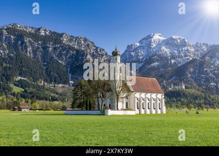 Wallfahrtskirche St. Coloman im Frühling, Sonne, hinter Schloss Neuschwanstein, Schwangau, Füssen, Ostallgaeu, Allgaeu, Schwaben, Bayern, Deutschland Stockfoto