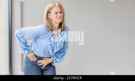 Eine blonde Frau leidet, weil sie Blinddarmschmerzen hat Stockfoto