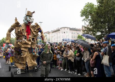 Skulptur der Künstlergruppe neben Zuschauern mit Regenschirmen bei der Straßenparade des 26. Karnevals der Kulturen in Berlin am 19. Mai 2024 Stockfoto