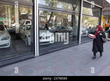 Eine Frau läuft am 04.07.2015 in Teheran, Iran, an einem Autohaus mit BMW und Mercedes Cars vorbei Stockfoto