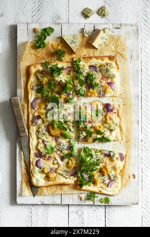 Hausgemachte Flammkuchen mit Blauschimmelkäse, Birnenchutney, roten Zwiebeln und Brunnenkresse auf weißem Holzgrund Stockfoto