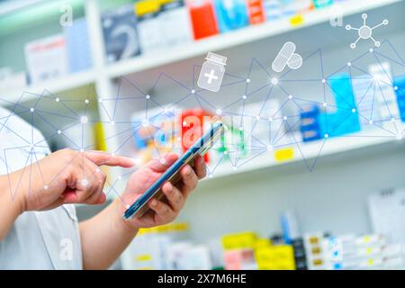 Ein Apotheker hält ein Mobiltelefon, um ein ärztliches Rezept zu erhalten, Medikamente zuzubereiten und Medikamente in einer Apotheke zu überprüfen. Stockfoto