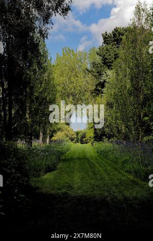 Ein sehr entfernter Blick auf die Happisburgh Church ist sorgfältig in die Gestaltung dieses Teils der Old Rectory Gardens in East Ruston, Norfolk, einbezogen Stockfoto