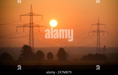 Algermissen, Deutschland. Mai 2024. Die Sonne geht hinter einer Hochspannungsleitung im Stadtteil Hildesheim auf. Die geplante Reform des europäischen Elektrizitätsmarktes soll am Dienstag die letzte Hürde räumen. Ende letzten Jahres haben die EU-staaten mit dem Europäischen Parlament eine Einigung über die Reform erzielt, mit der die Verbraucher künftig besser vor steigenden Strompreisen geschützt werden sollen. Quelle: Julian Stratenschulte/dpa/Alamy Live News Stockfoto