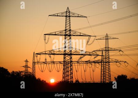 Algermissen, Deutschland. Mai 2024. Die Sonne geht hinter Hochspannungsleitungen im Stadtteil Hildesheim auf. Die geplante Reform des europäischen Elektrizitätsmarktes soll am Dienstag die letzte Hürde räumen. Ende letzten Jahres haben die EU-staaten mit dem Europäischen Parlament eine Einigung über die Reform erzielt, mit der die Verbraucher künftig besser vor steigenden Strompreisen geschützt werden sollen. Quelle: Julian Stratenschulte/dpa/Alamy Live News Stockfoto