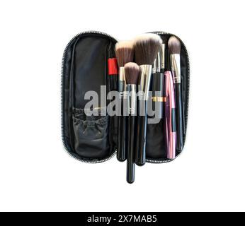 Ein Satz verschiedener Make-up-Bürsten ist in einem offenen schwarzen Reißverschlussetui ordentlich angeordnet. Studio auf weißem Hintergrund. Isoliert Stockfoto