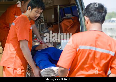 Gruppe von Sanitätern oder Notfallmedizinern (EMT) in einer orangen Uniform platziert ein Nacken-Kopf-Unfallopfer in einem Krankenwagen auf ein Bett. Dringend Stockfoto