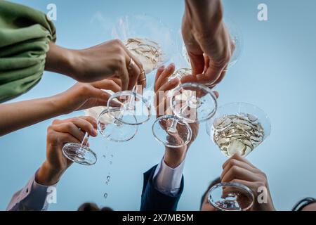 Gruppe von Leuten, die eine Brille mit Martini gegen den Himmel drücken während der Party Sommer draußen, Nahaufnahme Stockfoto