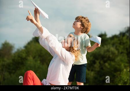 Muttertag. Mutter und Sohn campen. Kinderbetreuung. Leute, die sich im Freien amüsieren. Kinder spielen mit einfachen Papierflugzeugen an sonnigen Tagen. Familienfreundlicher Sommer Stockfoto