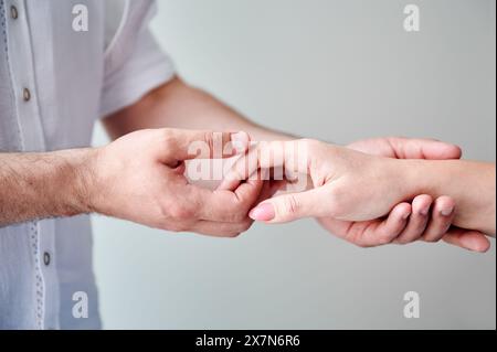 Nahaufnahme von zwei Händen, die eine zarte Berührung ausüben. Hände von Mann und Frau auf weißem neutralen Hintergrund. Der Mann hält die Hand seiner liebenswerten Frau. Konzept von Zuneigung, Unterstützung und gegenseitigem Respekt. Stockfoto