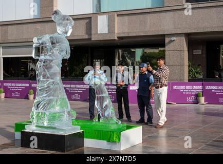 Die Menschen machen ein Foto der Eisskulptur, die unter der Hitzewelle in Delhi schmilzt, um die Auswirkungen der Hitzewellen im ganzen Land zu zeigen, als Teil eines Protestes eines Greenpeace-Aktivisten in der Select City Mall in Saket, New Delhi. Die 8 Fuß hohe Eisskulptur, die eine Frau mit einem Kind und einem Hund zeigt, stellt einige der gefährdetsten Gemeinschaften dar, die von Hitzewellen und anderen extremen Wetterereignissen betroffen sind. Während es in der glühenden Sonne Delhis schmilzt, sendet es eine Botschaft mit dem Titel „Act Before We Melt Away“, in der die National Disaster Management Authority aufgefordert wird, Hitzewellen als nationale Katastrophe zu erklären. (Foto: Pradeep Gaur/S Stockfoto