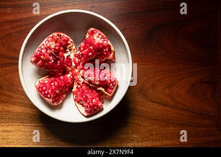 Granatapfel in Keramikschale auf Holztisch. Stockfoto