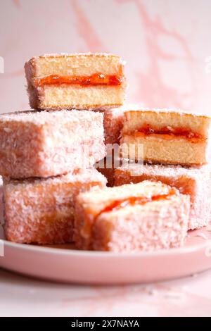 Australian Pink Lamington Small Square Cakes mit Erdbeermarmelade und Kokosnuss. Stockfoto