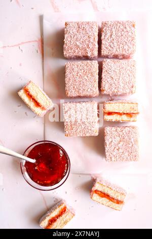 Australian Pink Lamington Small Square Cakes mit Erdbeermarmelade und Kokosnuss. Stockfoto