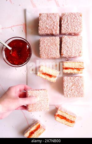 Australian Pink Lamington Small Square Cakes mit Erdbeermarmelade und Kokosnuss. Stockfoto