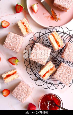 Australian Pink Lamington Small Square Cakes mit Erdbeermarmelade und Kokosnuss. Stockfoto