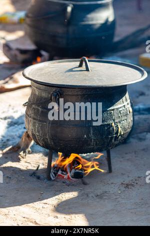 Dreibeiniger afrikanischer schwarzer gusseiserner Topfkessel, kocht draußen, kocht langsam Stockfoto