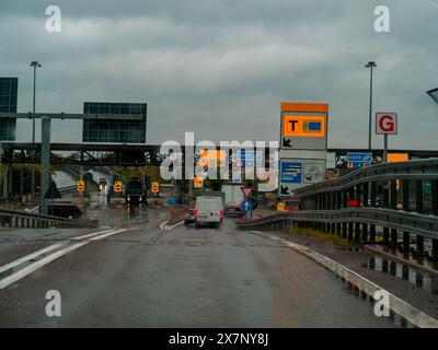 Piacenza, Italien - 22. April 2024 Annäherung an eine Mautstelle auf einer nassen Straße bei regnerischem Wetter, mit verschiedenen Schildern und einem Van im Blick, regnerischer Tag auf Motorw Stockfoto