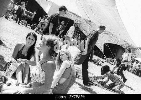 CROWD, HEATWAVE, NME STAGE, GLASTONBURY 95: Festivalbesucher krachen auf dem Gras und trinken Wasser in der extremen Sommerhitze am Acoustic Stage Zelt beim Glastonbury Festival, Pilton Farm, Somerset, England, 24. Juni 1995. 1995 feierte das Festival sein 25-jähriges Bestehen. Viele Menschen hatten an dem besonders heißen Wochenende Probleme mit dem Hitzschlag. Foto: ROB WATKINS Stockfoto