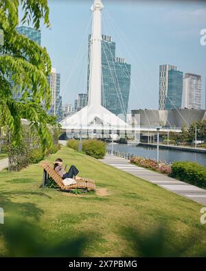 Frau, die auf einer Bank sitzt und im Central Park, Incheon, Südkorea, eine Pause macht Stockfoto